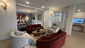 Ein modernes Wohnzimmer mit roten und grauen Sofas, einem Couchtisch und einem Fernseher auf einer Holzkonsole.