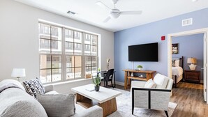 Ein modernes Wohnzimmer mit Sofa, Sesseln, Couchtisch und einem an der Wand montierten Flachbildfernseher.