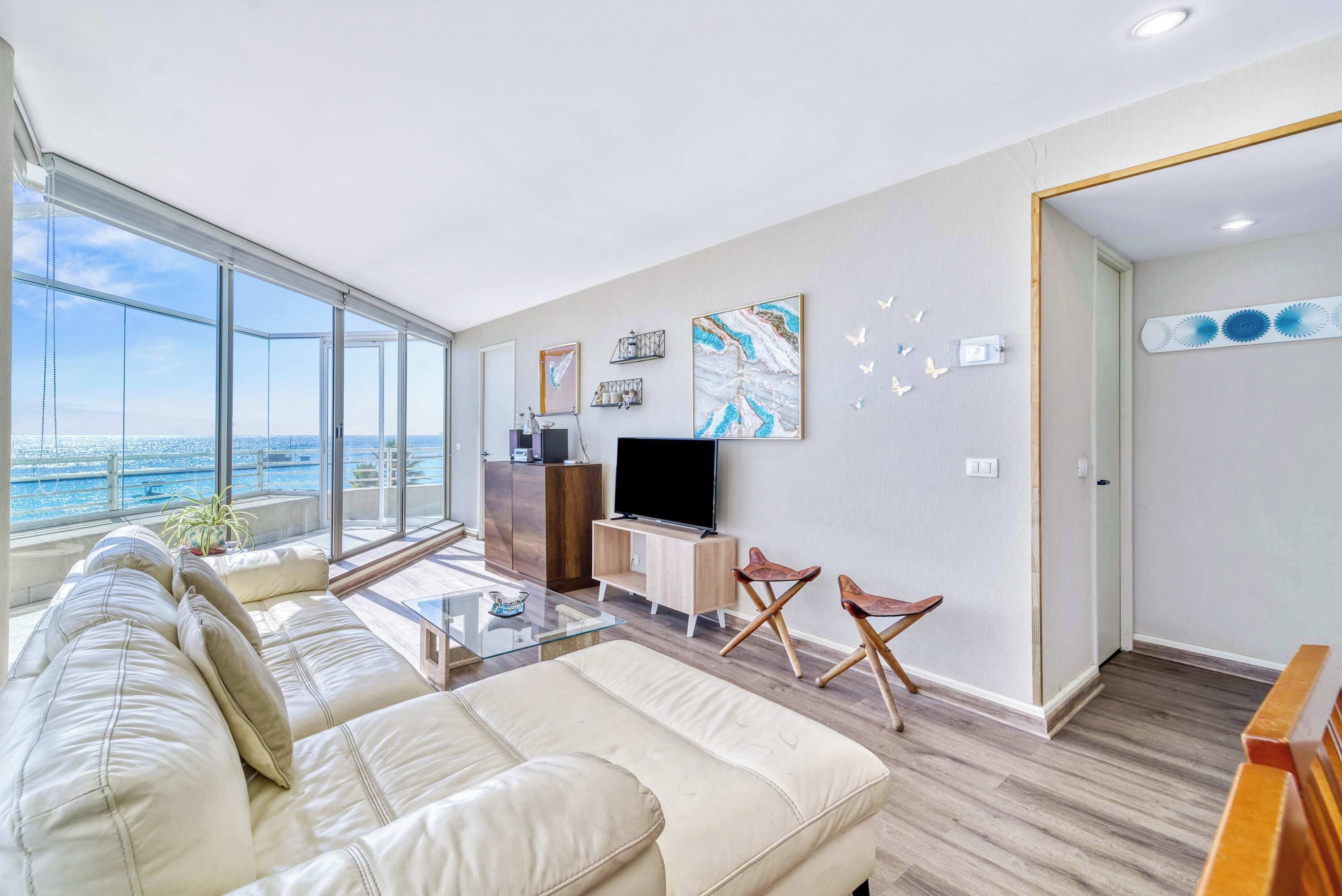 A modern living room with a large window, a sofa, a TV, and a wooden cabinet.
