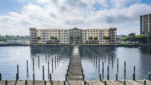 Un hotel frente al agua con un patio central, varios pisos y un muelle que se extiende hacia el agua.