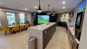 A modern kitchen with a central island, a dining area with yellow chairs, and a large window with a view of a golf course. - Landing | Spectacular 1BD, Gym (Fort Myers)