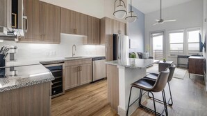 Une cuisine moderne avec des meubles en bois, des appareils électroménagers en acier inoxydable et un coin bar avec des tabourets.