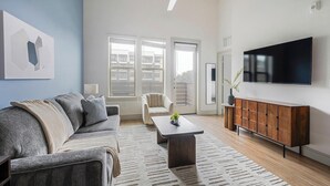 Ein modernes Wohnzimmer mit grauem Sofa, einem Couchtisch, einem Holzschrank und einem Flachbildfernseher.