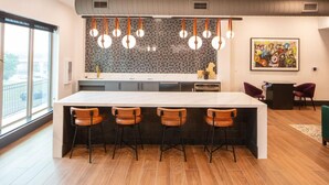 Una cocina moderna con una isla grande, taburetes de bar, luces colgantes y vistas a la ciudad.