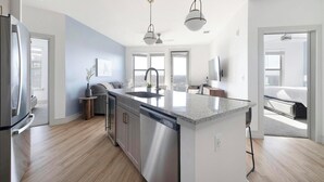 Una cocina moderna con una isla central, electrodomésticos de acero inoxidable y vistas al área de estar.