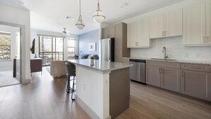 A modern kitchen with a central island, stainless steel appliances, and light wood cabinetry. - Landing | Spectacular 1BD, Clubhouse, Pool (Austin)