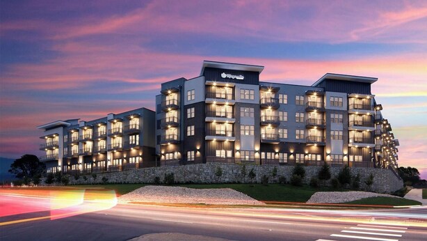 A multi-story hotel with balconies, a stone facade, and a well-lit entrance. - Landing | Spectacular 1BD, Clubhouse, Pool (Austin)