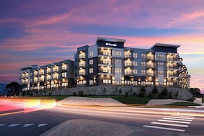 A multi-story hotel with balconies, a stone facade, and a well-lit entrance. - Landing | Amazing 1BD, Pool, Clubhouse (Austin)