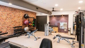 Ein Fitnessraum mit Gewährterhomen, einem an der Wand montierten Medizinballhalter und einer Spiegelwand.