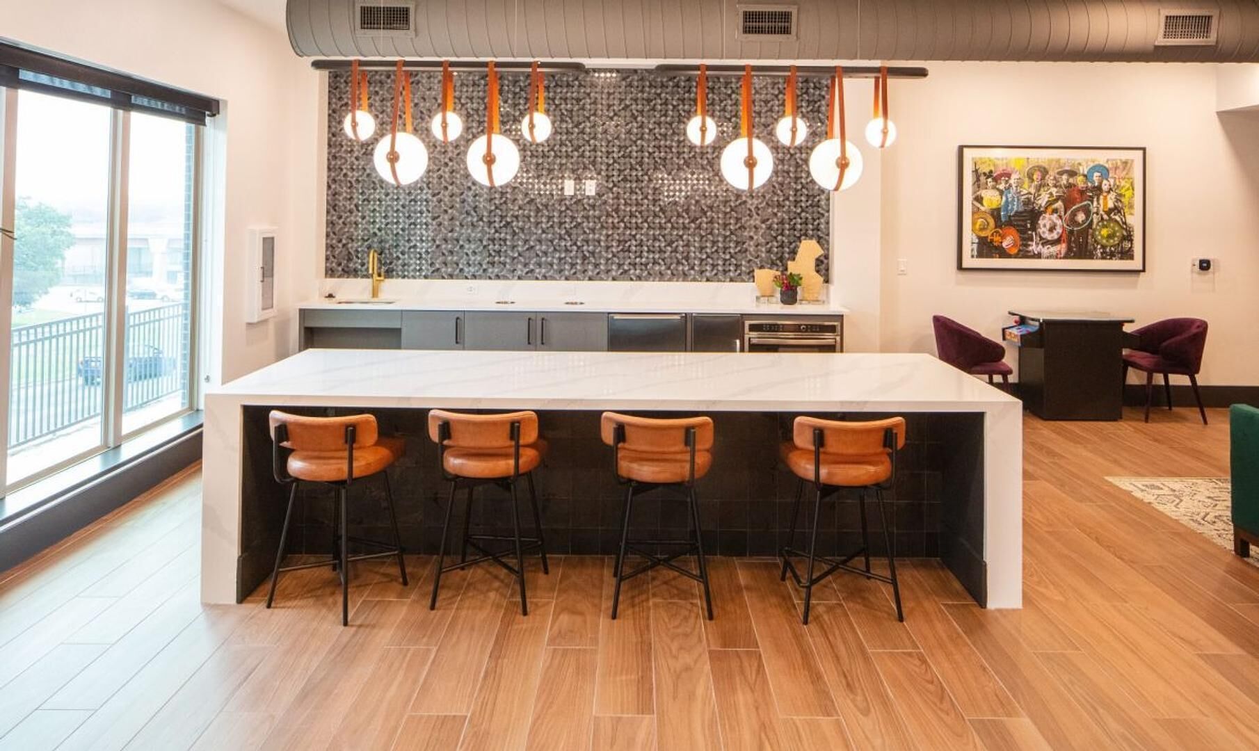 A modern kitchen with a large island, bar stools, pendant lights, and a city view.