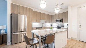 Een moderne keuken met een centraal eiland, roestvrijstalen apparatuur en houten keukenkastjes.