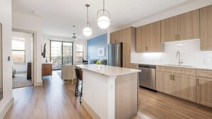 Een moderne keuken met houten kastjes, een centraal eiland, roestvrijstalen apparatuur en hanglampen.