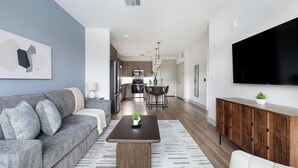Un salon moderne avec un canapé gris, une table basse et un téléviseur fixé au mur.