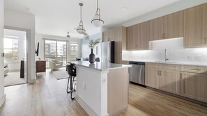 Une cuisine moderne avec des meubles en bois, un réfrigérateur en acier inoxydable et un îlot central doté de tabourets de bar.