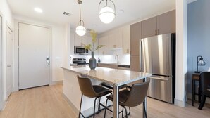A modern kitchen with a central island, stainless steel appliances, and pendant lighting. - Landing | Beautiful 1BD, Pool, Clubhouse (Austin)