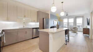 A modern kitchen with a central island, stainless steel appliances, and pendant lighting. - Landing | Beautiful 1BD, Pool, Clubhouse (Austin)