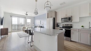 A modern kitchen with a central island, stainless steel appliances, and a view to the outside. - Landing | Beautiful 1BD, Pool, Clubhouse (Austin)