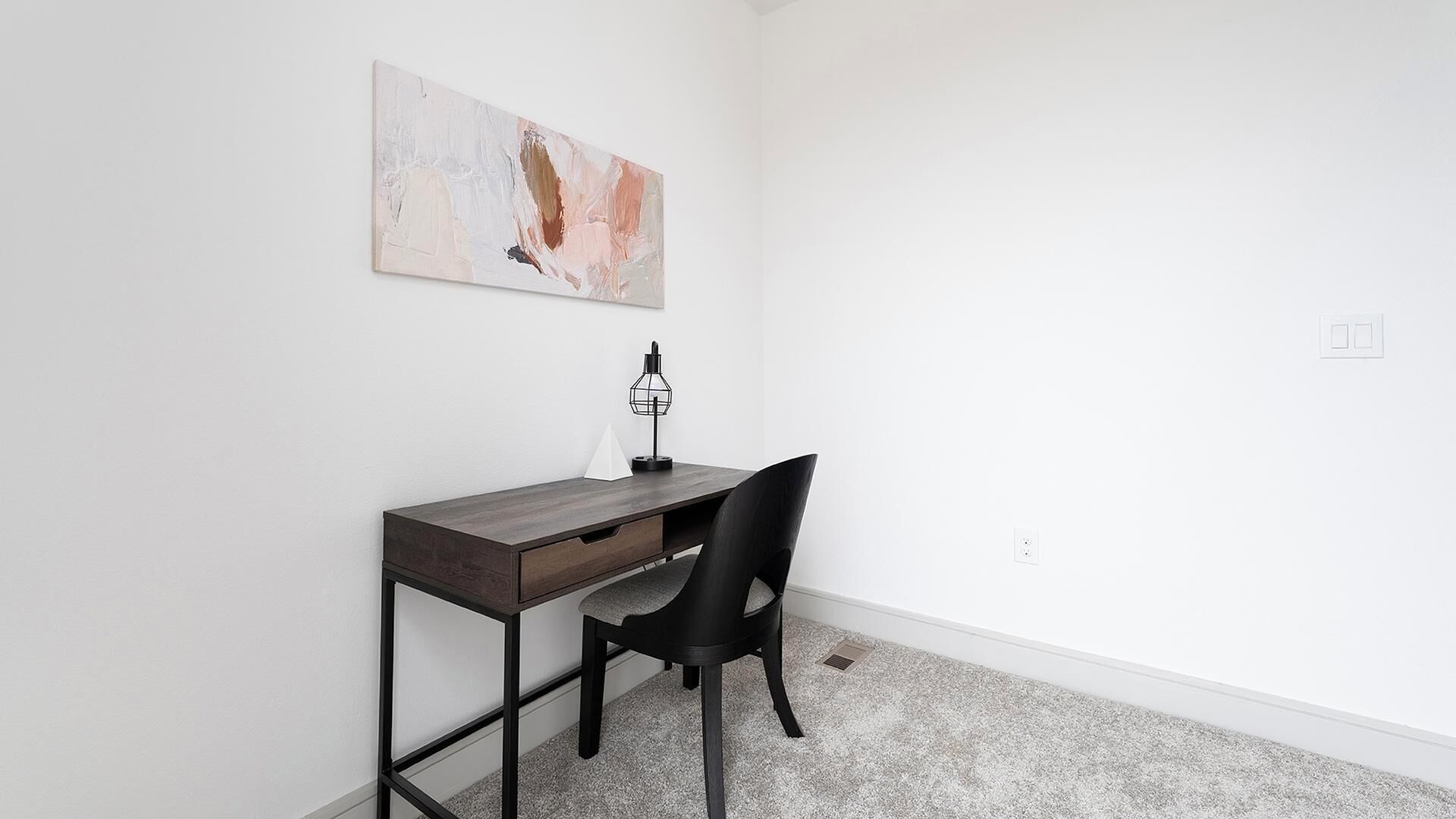 Une pièce comprenant un bureau, une chaise et un tableau accroché au mur.