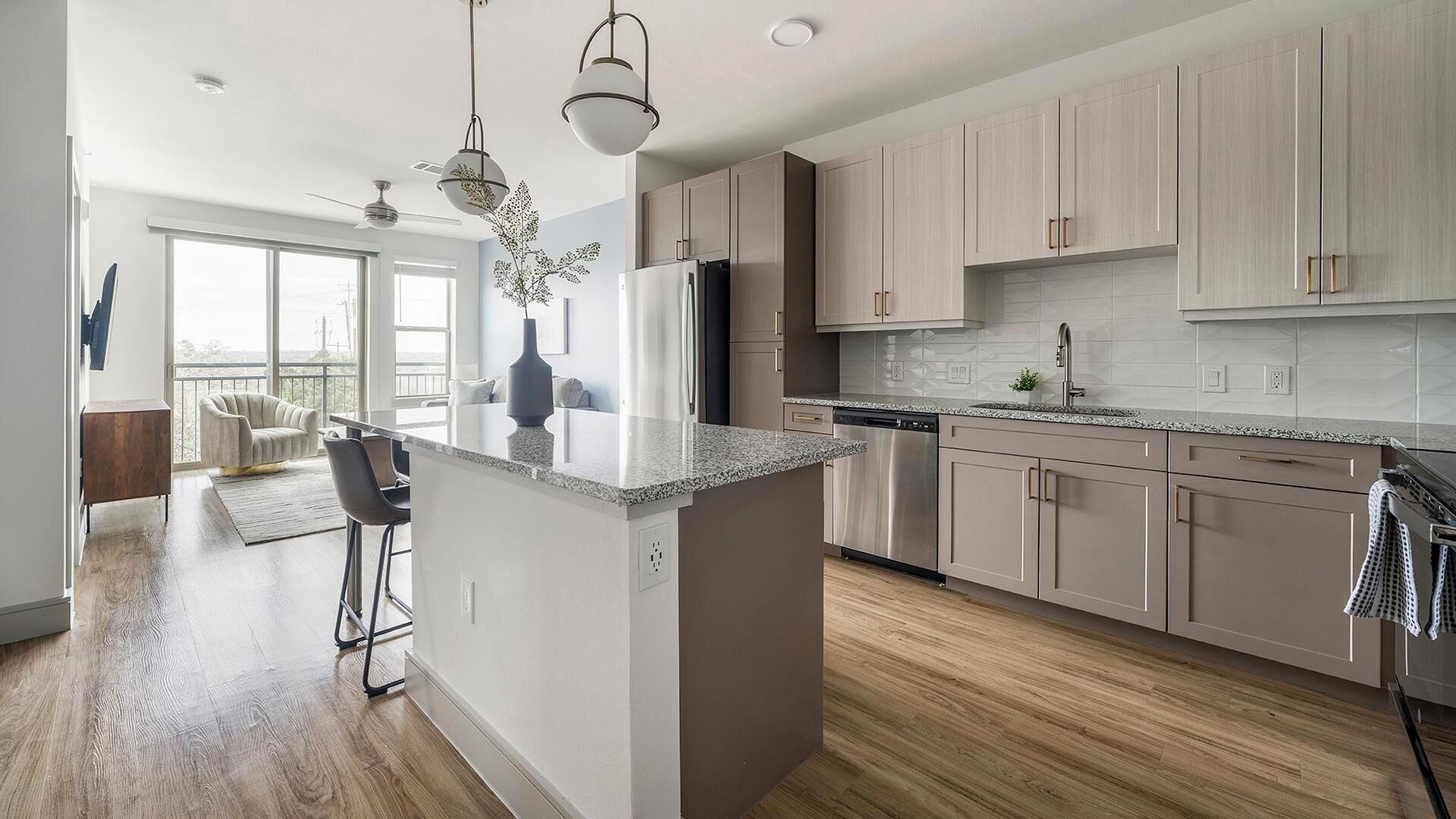 A modern kitchen with a central island, stainless steel appliances, and light wood cabinetry.
