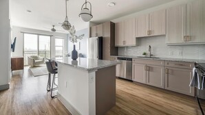 Une cuisine moderne dotée d’un îlot central, d’appareils électroménagers en acier inoxydable et de meubles de rangement en bois clair.