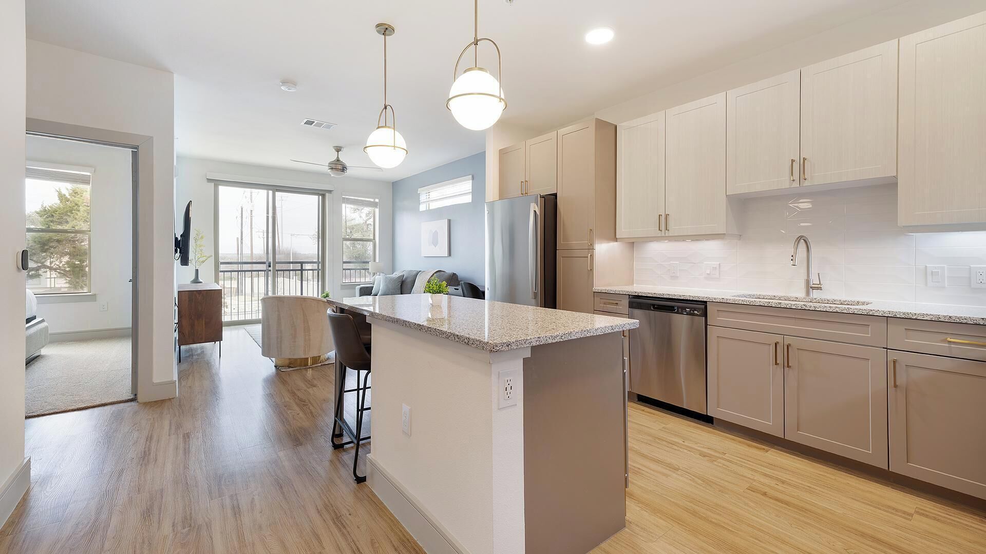 A modern kitchen with a central island, stainless steel appliances, and light wood cabinetry.