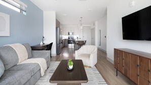 A modern living room with a sofa, coffee table, and TV. - Landing | Stunning 1BD, Clubhouse, Gym (Austin)