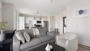 Uma sala de estar moderna com um sofá cinzento, uma poltrona bege e uma mesa de centro com objetos decorativos.