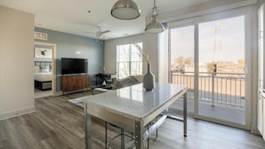 Uma sala de estar moderna com televisão de tela plana, mesa de jantar e varanda com vista para a cidade.
