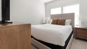 Ein Hotelzimmer mit Bett, Nachttischen, Fernseher und einem Fenster mit Jalousien.