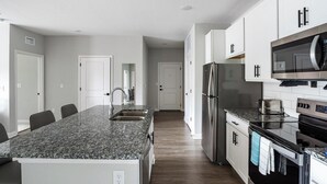 Eine moderne Küche mit Granit-Arbeitsplatten, Edelstahlgeräten und weißen Schränken.