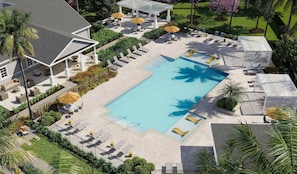 A rooftop pool area with lounge chairs and umbrellas, surrounded by greenery and a building with a white facade.