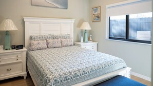 Quarto com cama, mesas de cabeceira, janela e obras de arte nas paredes.