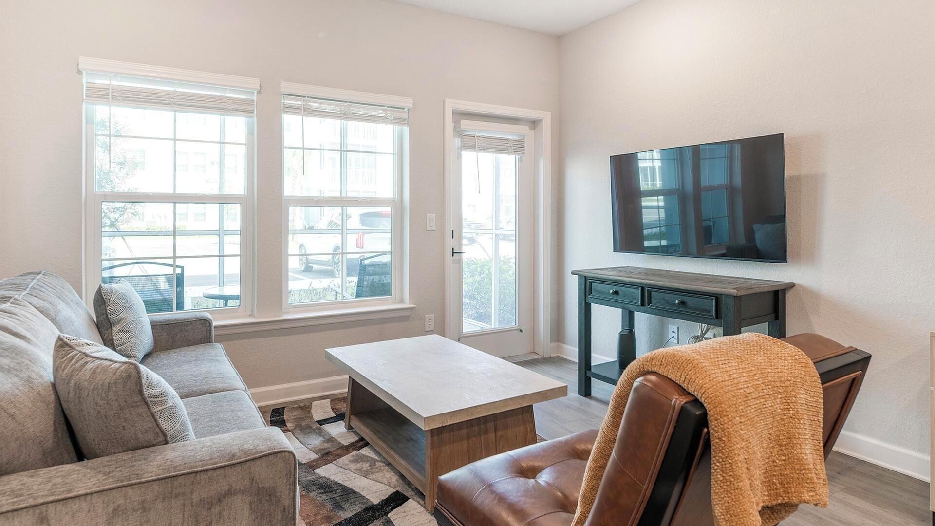 A living room with a sofa, coffee table, TV, and a view of the outside.