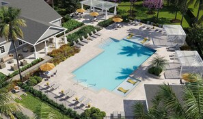 A rooftop pool area with lounge chairs and umbrellas, surrounded by greenery and a building with a white facade.