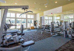 Ein Fitnessstudio mit Laufbändern, Krafttrainingsgeräten und Kurzhanteln.