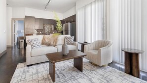 Ein modernes Wohnzimmer mit Sofa, Sessel, Couchtisch und einer dekorativen Vase.