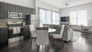 Eine moderne Küche mit integriertem Mikrowellenherd, Backofen und Kühlschrank. Ein Essbereich mit rundem Tisch und Stühlen ist vorhanden.