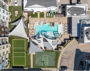 Vista aérea de um hotel com piscina, quadras de tênis e quadra de basquete.