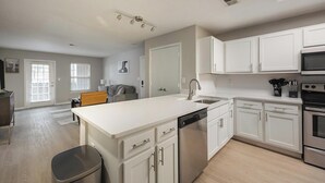 Una cocina moderna con armarios blancos, lavavajillas, horno y microondas.