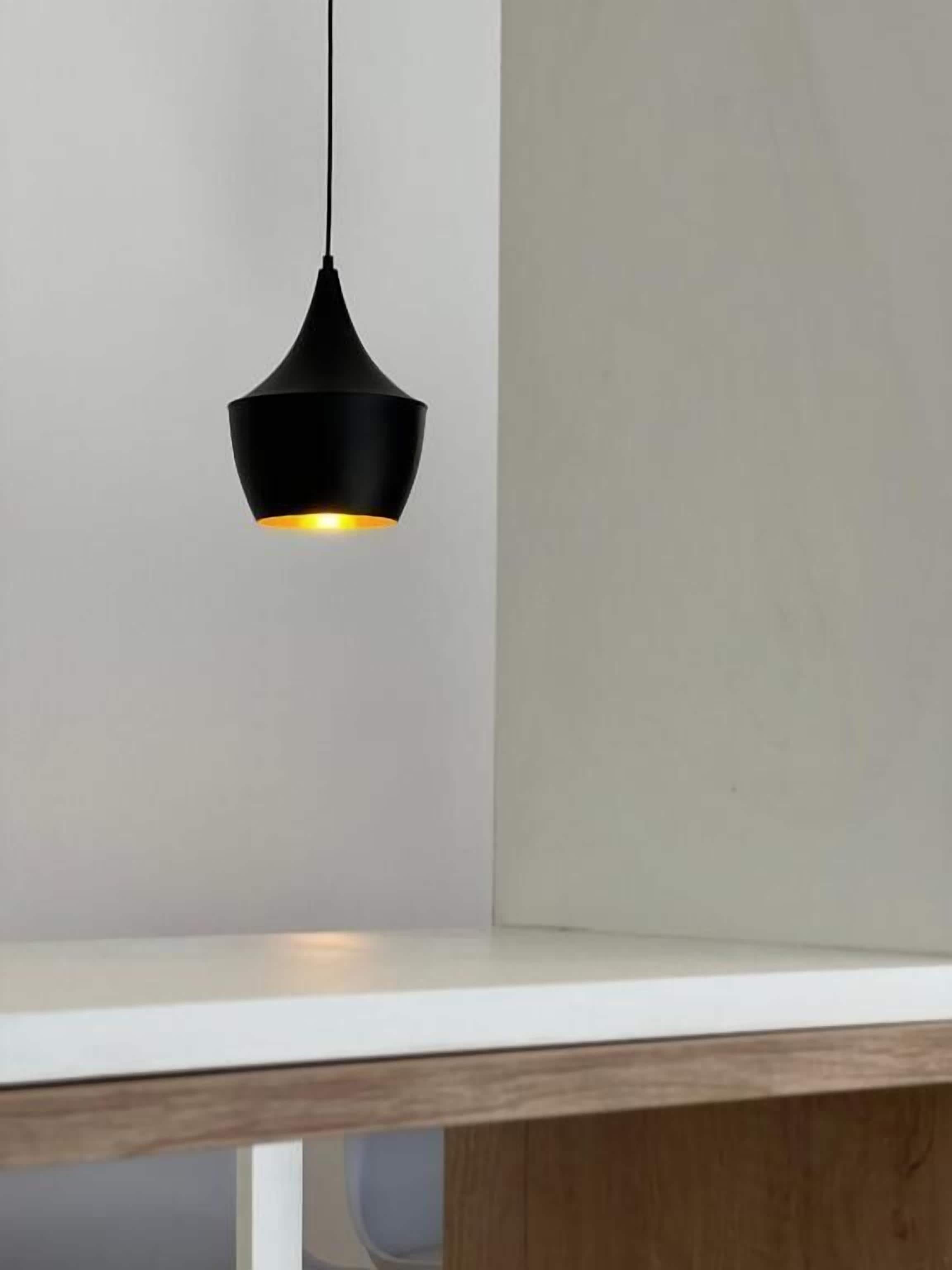 Una lámpara colgante con pantalla negra y una luz cálida.
