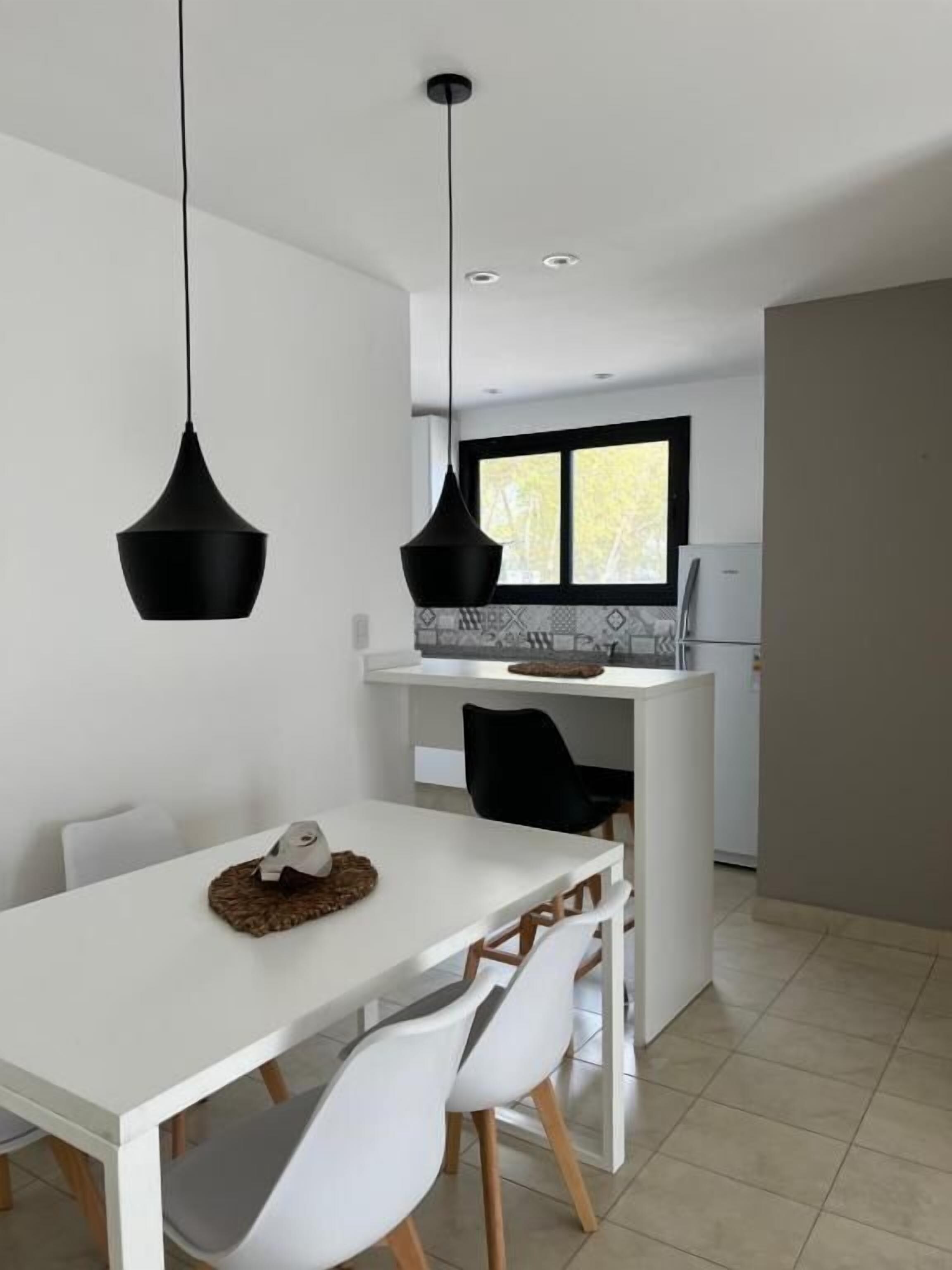 Une cuisine moderne avec des meubles blancs, un plan de travail noir et une fenêtre au-dessus de l’évier.