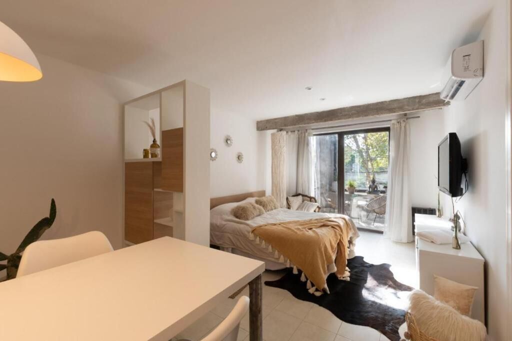 A modern bedroom with a bed, a desk, a TV, and a sliding glass door leading to a balcony.