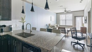 Una cocina moderna con encimeras de granito, lavavajillas y una zona de comedor con mesa y sillas.