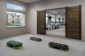 A gym with exercise equipment, a sliding door, and a view of buildings outside.