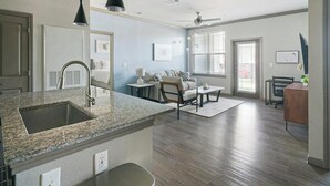 A modern kitchen with granite countertops, a built-in sink, and a ceiling fan. - Landing | Incredible 2BD in Eastpoint (Baytown)