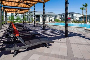 A poolside area with lounge chairs and a covered seating area. - Landing | Modern 2BD in Eastpoint (Baytown)
