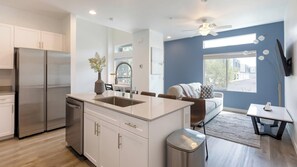 Una cocina moderna con una isla central, electrodomésticos de acero inoxidable y un comedor con sofá y mesa.