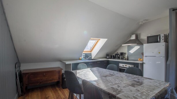 Eine kompakte Küche mit Essbereich, einem Holztisch und einem kleinen Fenster.