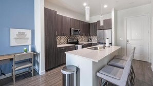 Una cucina moderna con mobili in legno scuro, un frigorifero in acciaio inossidabile, un forno a microonde e una grande isola con sgabelli da bar.
