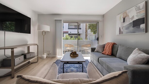 Una sala de estar moderna con un sofá, una mesa de centro y un televisor montado en la pared.